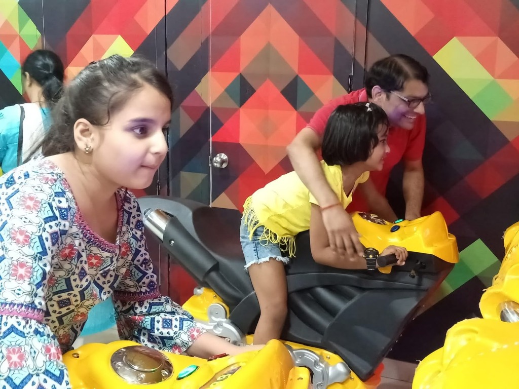 Father and kids playing arcade racing games at Phoenix United Bareilly